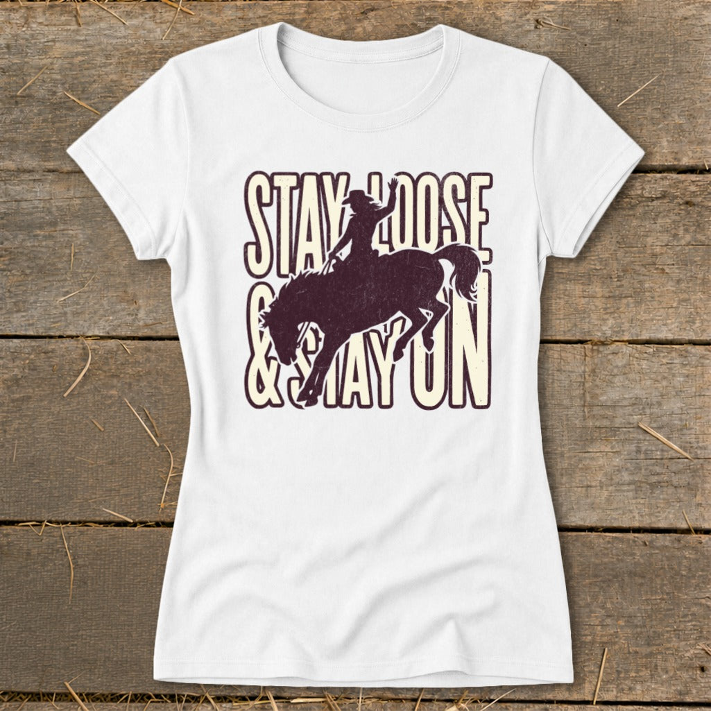White t-shirt with cowboy riding bronco graphic and text "STAY LOOSE & STAY ON".