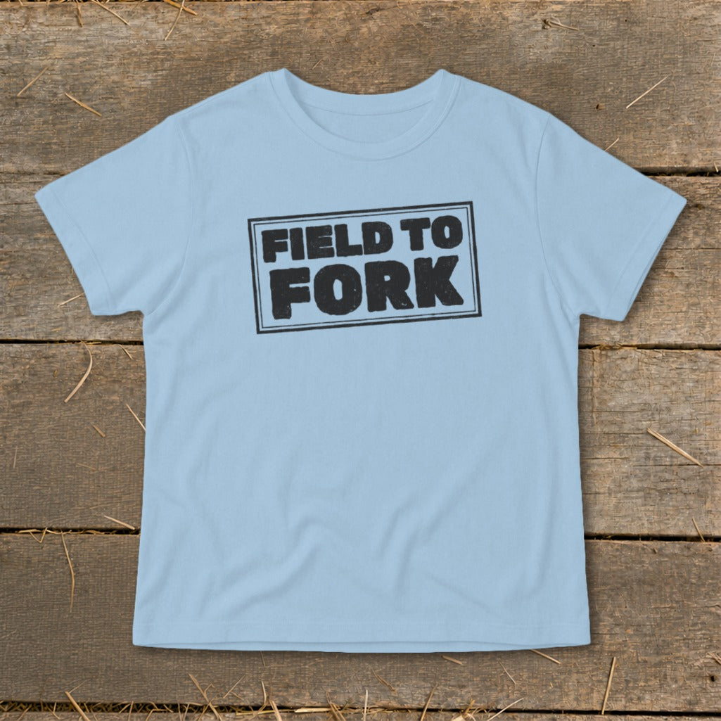 Light blue t-shirt featuring a black rectangle stamp with the words Field To Fork displayed centrally.