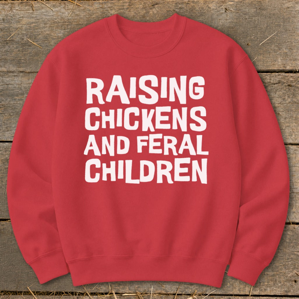 Red sweatshirt with white text: Raising Chickens and Feral Children.