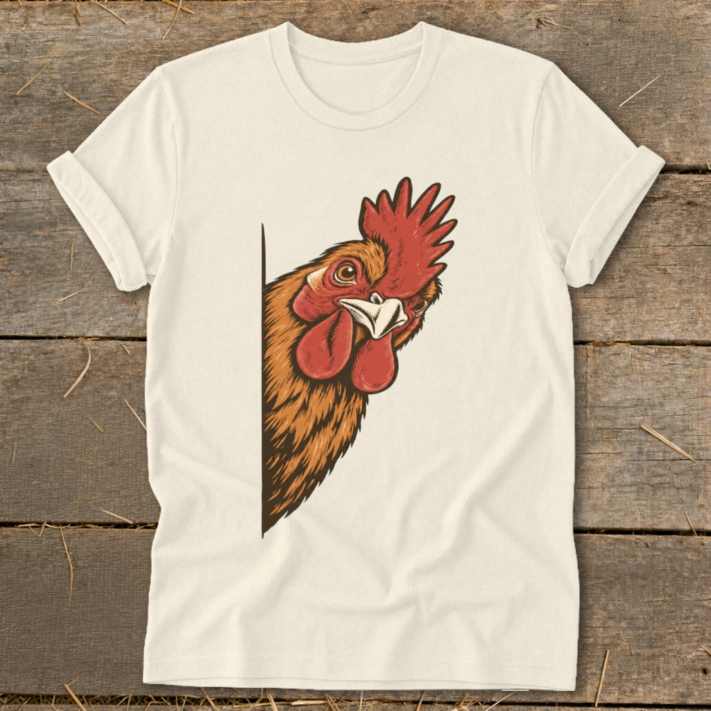 Rooster peeking from behind a white t-shirt on a wooden background.