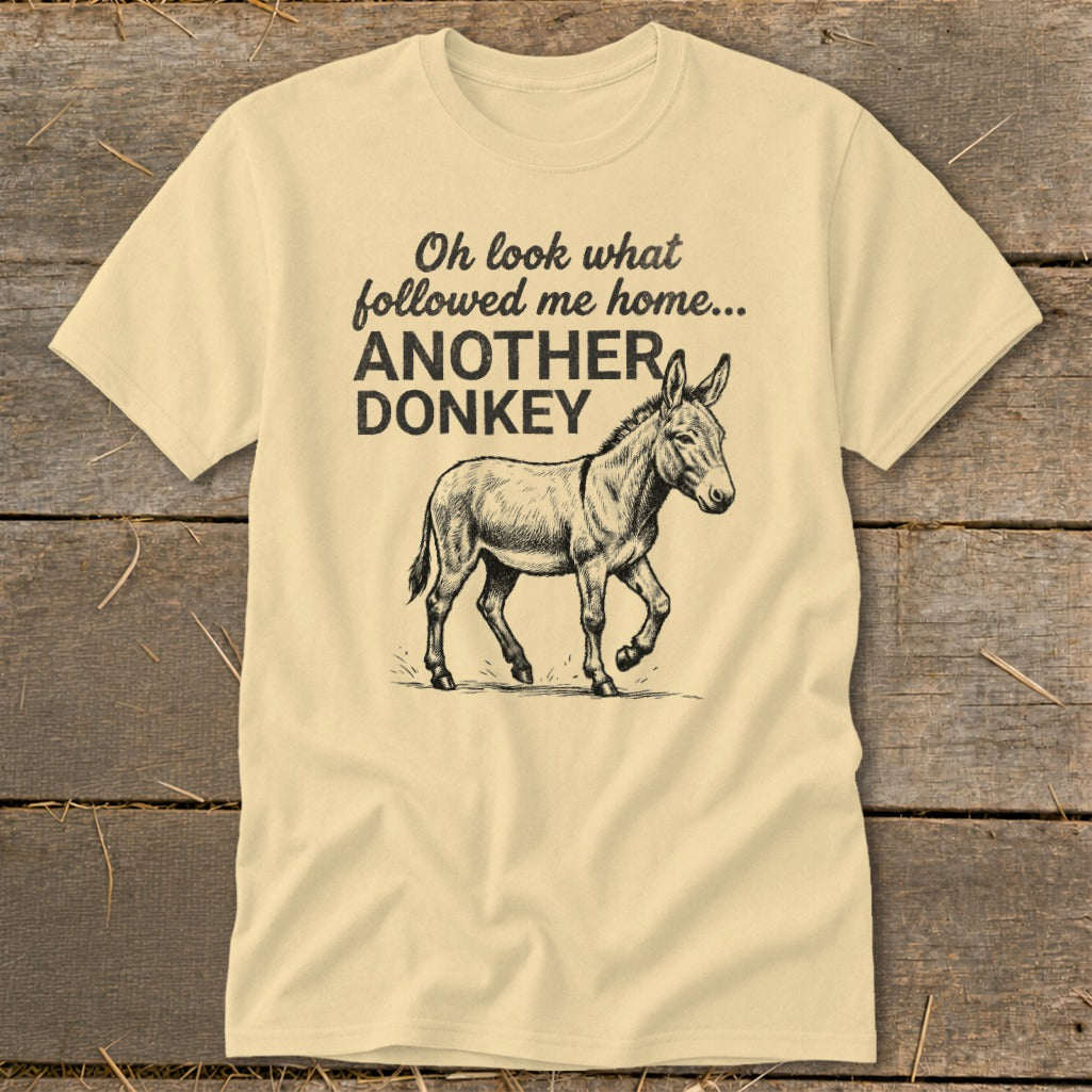 Light yellow t-shirt with black text and donkey graphic saying "Oh look what followed me home... ANOTHER DONKEY".