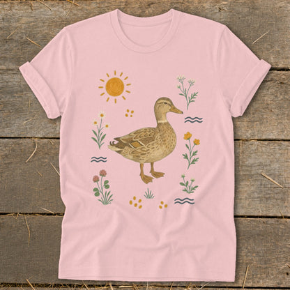 Pink t-shirt with a duck illustration surrounded by flowers, sun, and water waves.