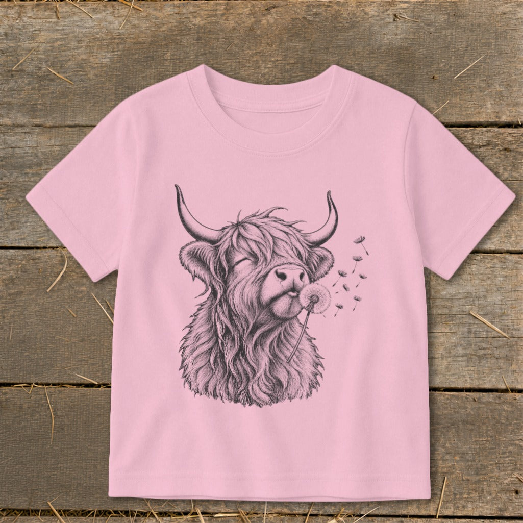 Pink t-shirt with a sketch of a Highland cow blowing on a dandelion.