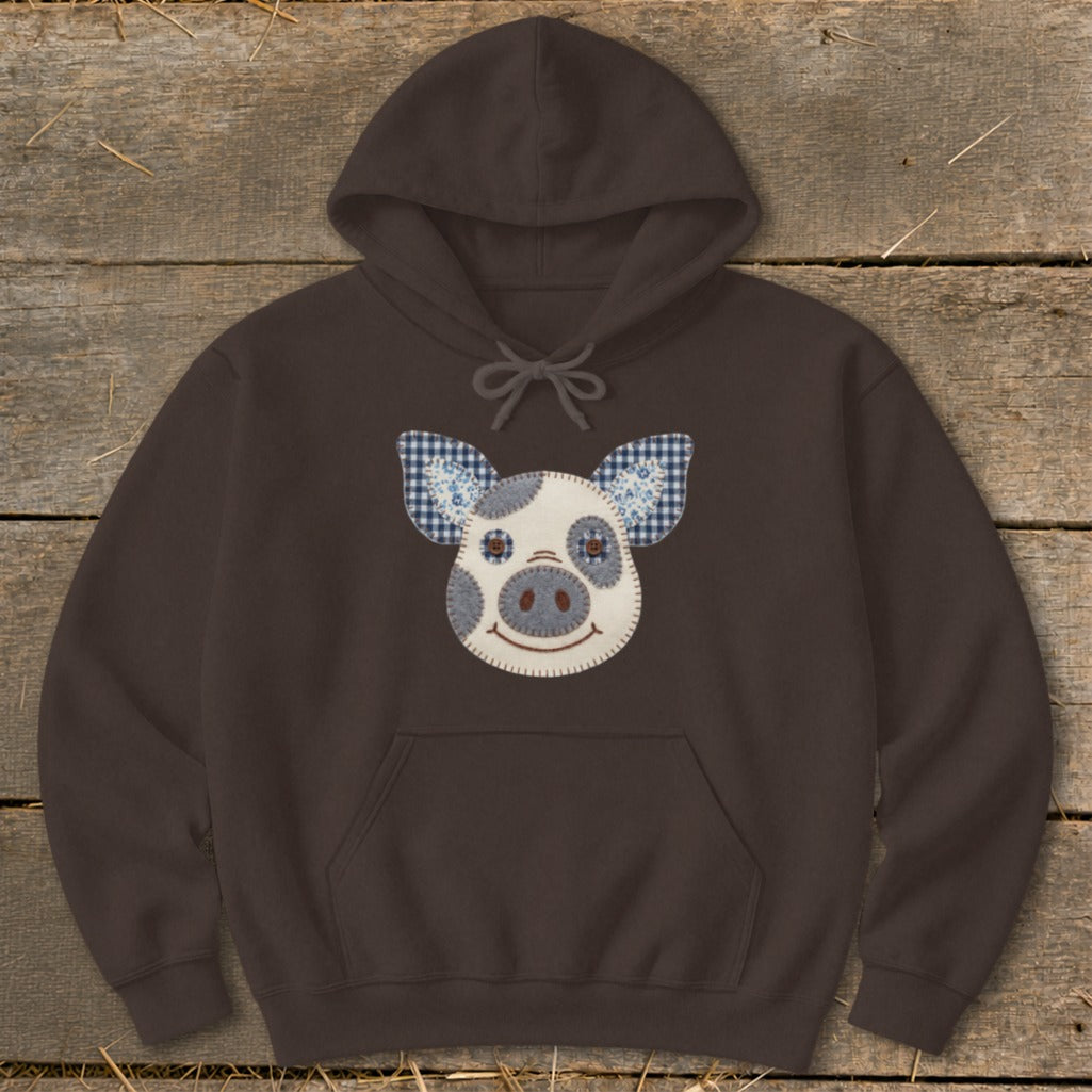 Brown hoodie with a stitched pig face applique featuring plaid ears and button eyes.
