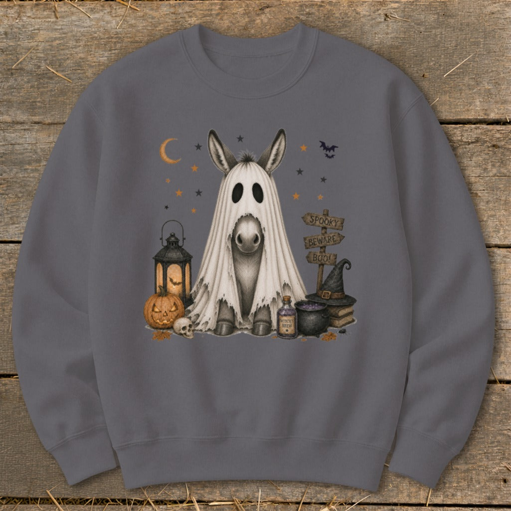 Donkey in a ghost costume surrounded by Halloween decorations, including a pumpkin and witch hat.