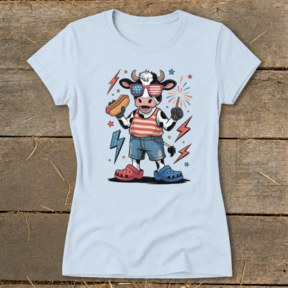 Cartoon cow in patriotic sunglasses holding hot dog and sparkler with lightning bolts.
