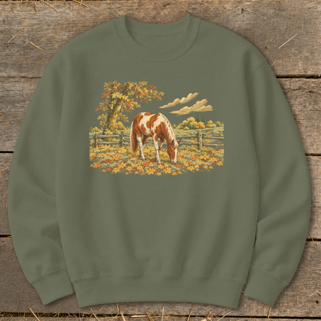 Horse grazing in autumn field with colorful leaves and wooden fence.