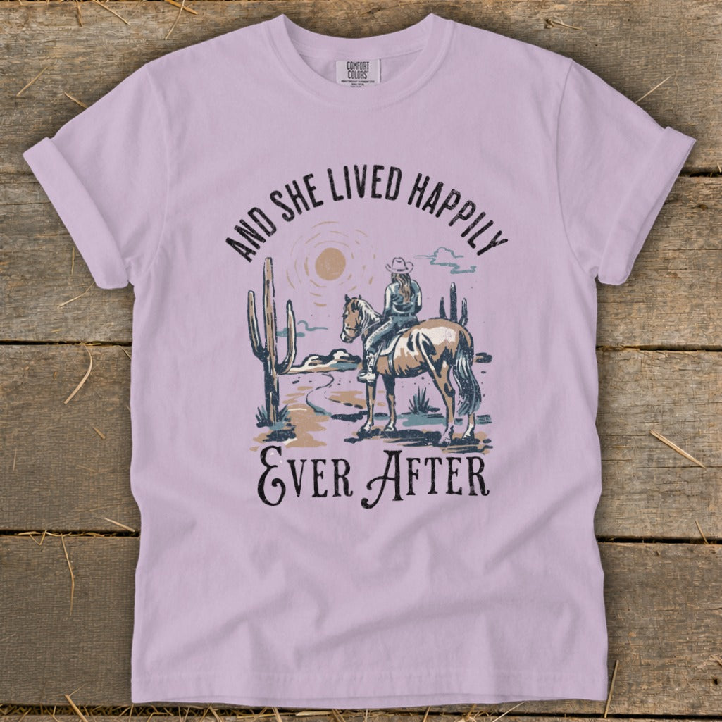 Lavender t-shirt with woman on horse in desert scene and text "And She Lived Happily Ever After".