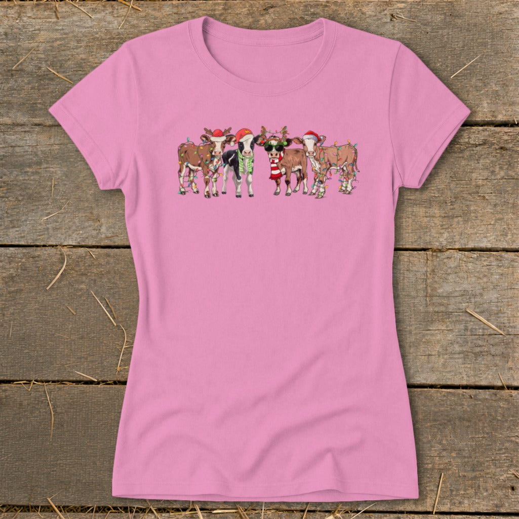 Pink t-shirt featuring a group of cartoon cows wearing Christmas hats and lights.