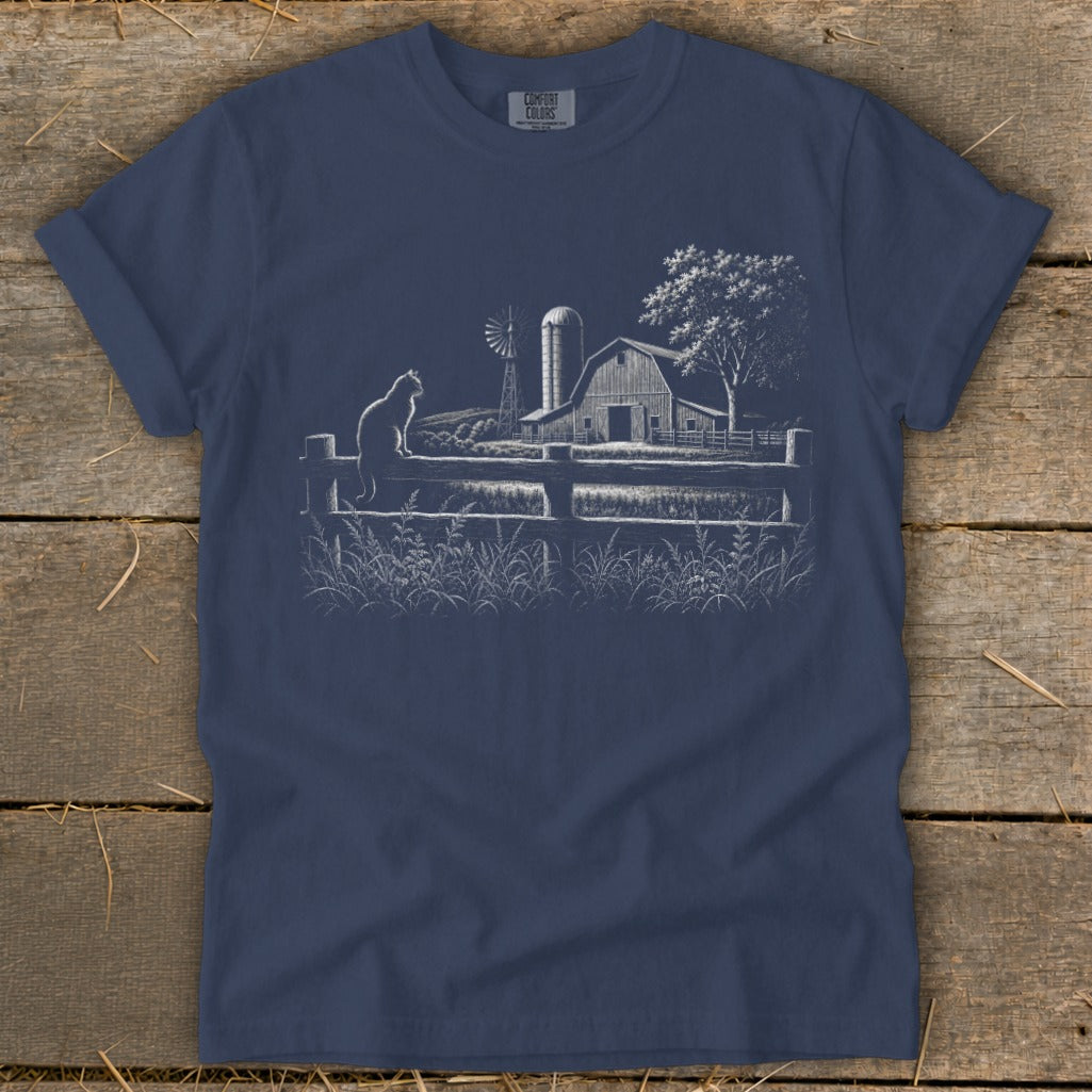 T-shirt with a white line drawing of a cat on a fence, barn, windmill, and tree.