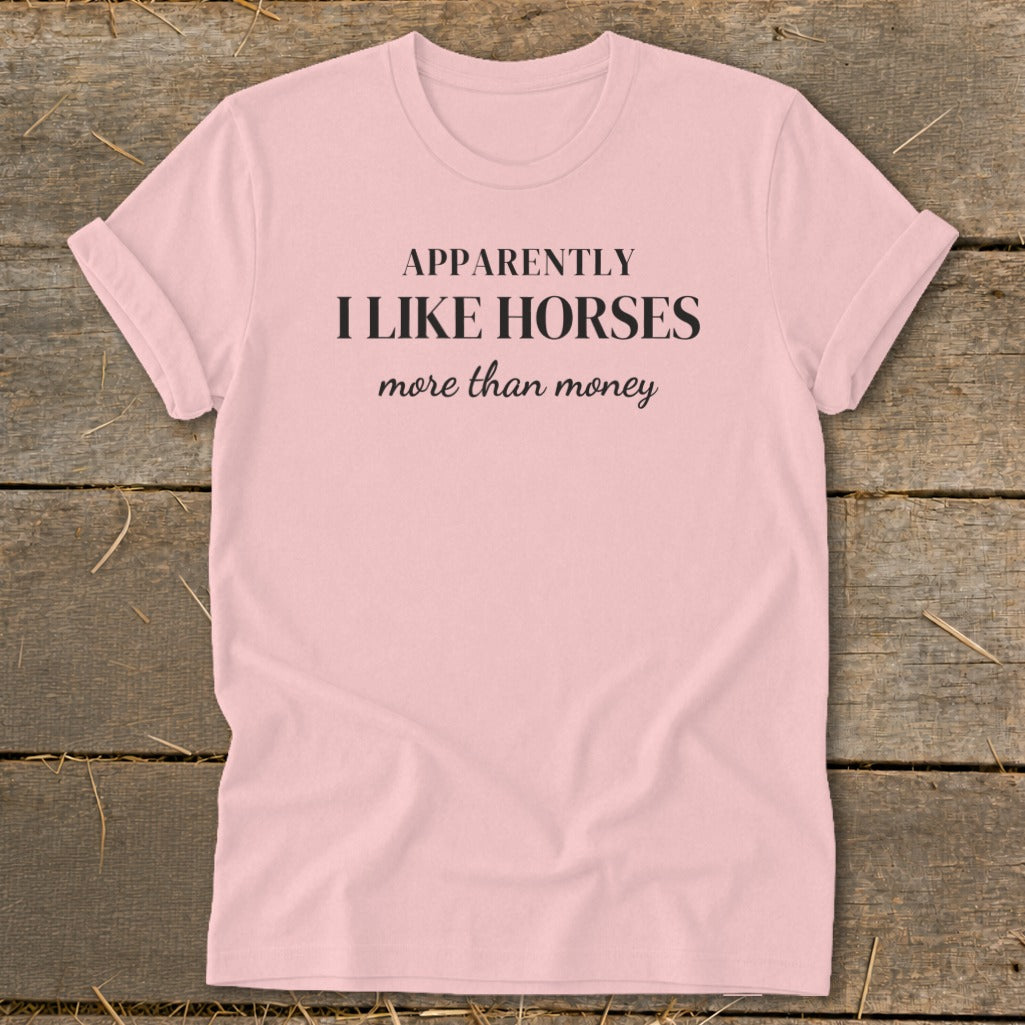 Pink t-shirt with black text that reads "APPARENTLY I LIKE HORSES more than money".