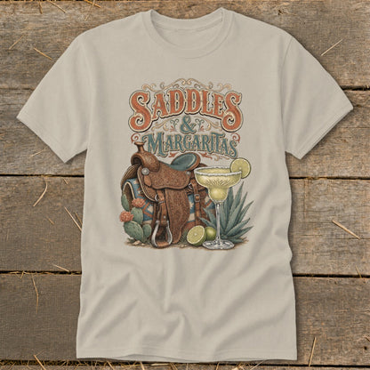 "Saddles & Margaritas" text with a Western saddle and margarita on a light tan t-shirt.