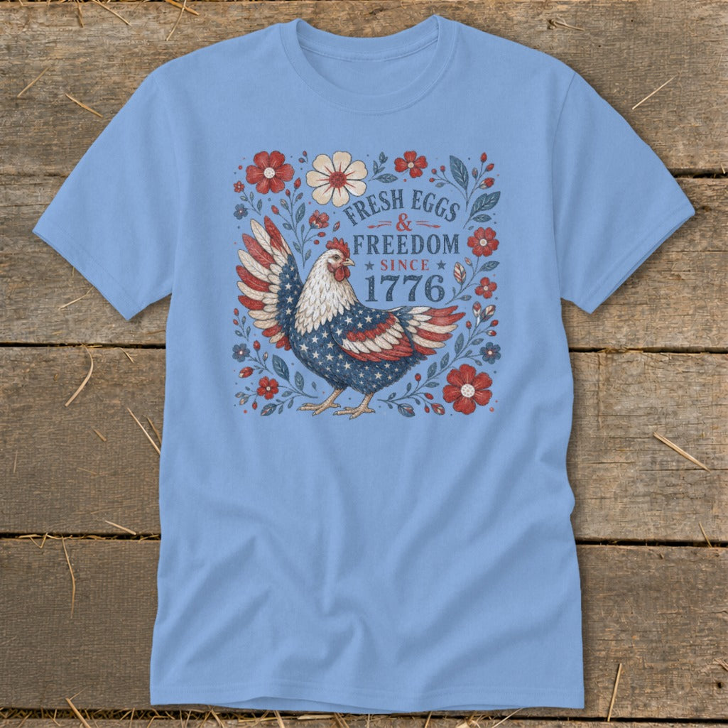 Light blue t-shirt with patriotic chicken graphic and text "Fresh Eggs & Freedom Since 1776".