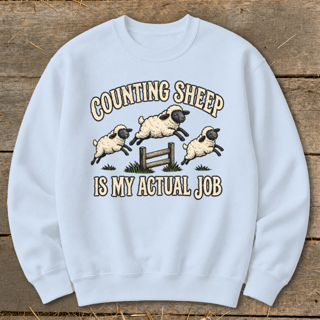Light blue sweatshirt with cartoon sheep jumping over a fence and text.
