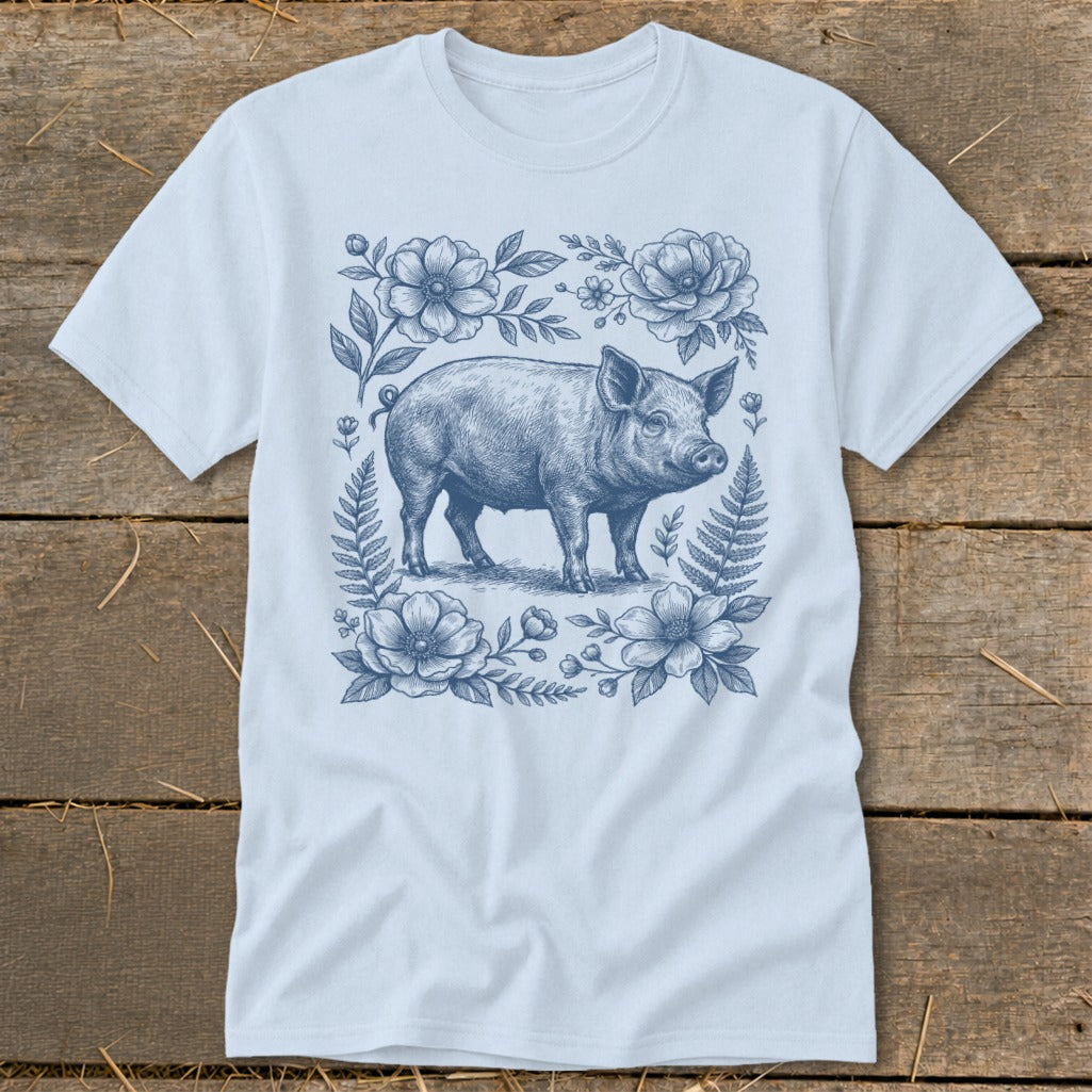 Light blue t-shirt with a blue ink drawing of a pig surrounded by flowers and ferns.