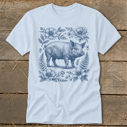 Light blue t-shirt with a blue ink drawing of a pig surrounded by flowers and ferns.