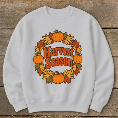 White sweatshirt with "Harvest Season" text surrounded by a pumpkin and leaf wreath.