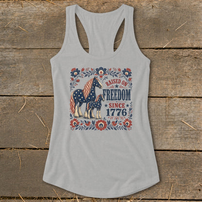 Grey tank top with patriotic horses and floral border, text reads "Raised on Freedom Since 1776".