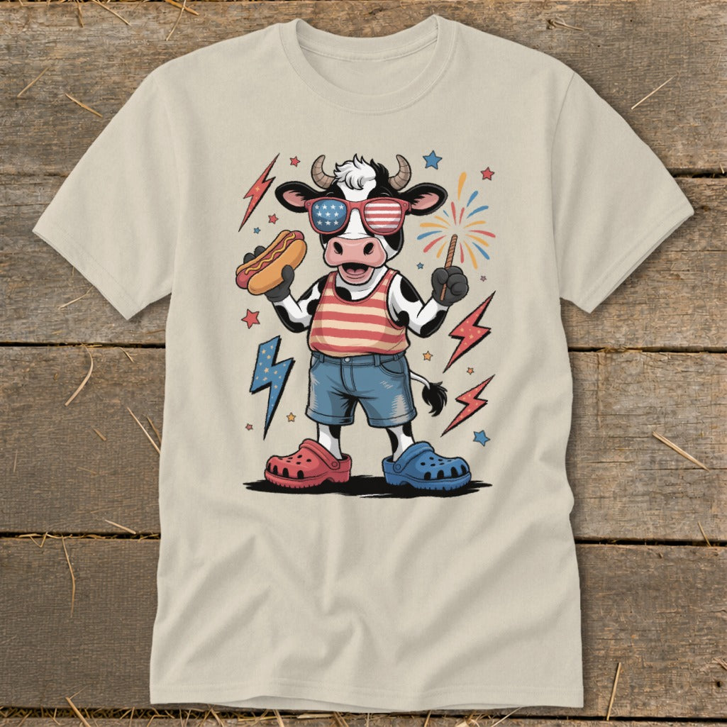 Cartoon cow wearing American flag sunglasses, holding hot dog and sparkler.