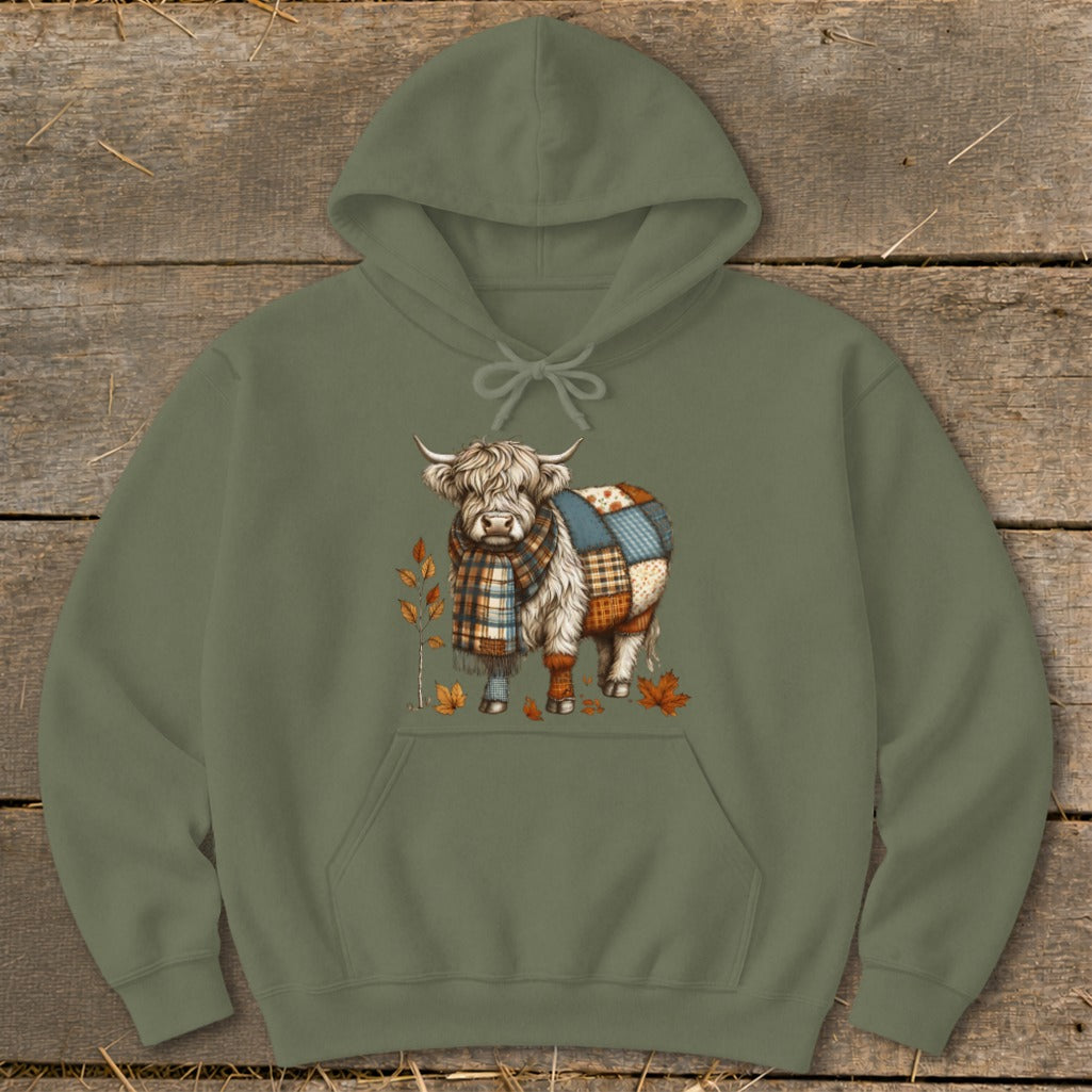 Highland cow wearing a plaid scarf and patchwork body, with autumn leaves.