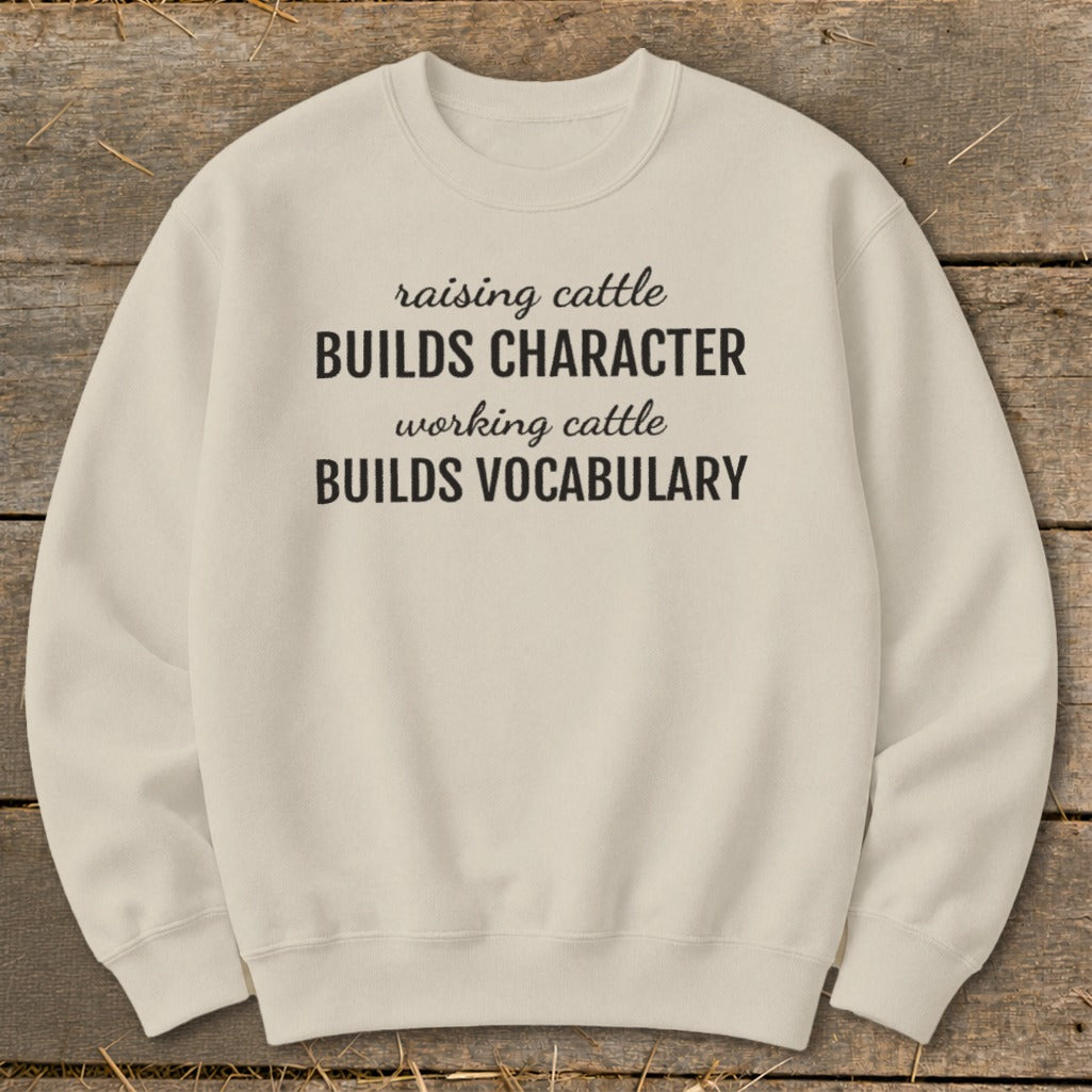 Cream sweatshirt with text "raising cattle BUILDS CHARACTER working cattle BUILDS VOCABULARY".