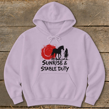 Light purple hoodie with black silhouette of horse and rider at sunrise. Text reads "SUNRISE & STABLE DUTY".
