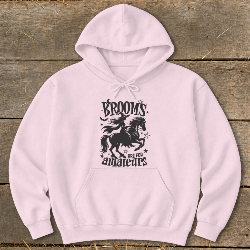 Pink hoodie with black graphic of witch on horse and "Brooms are for amateurs" text.
