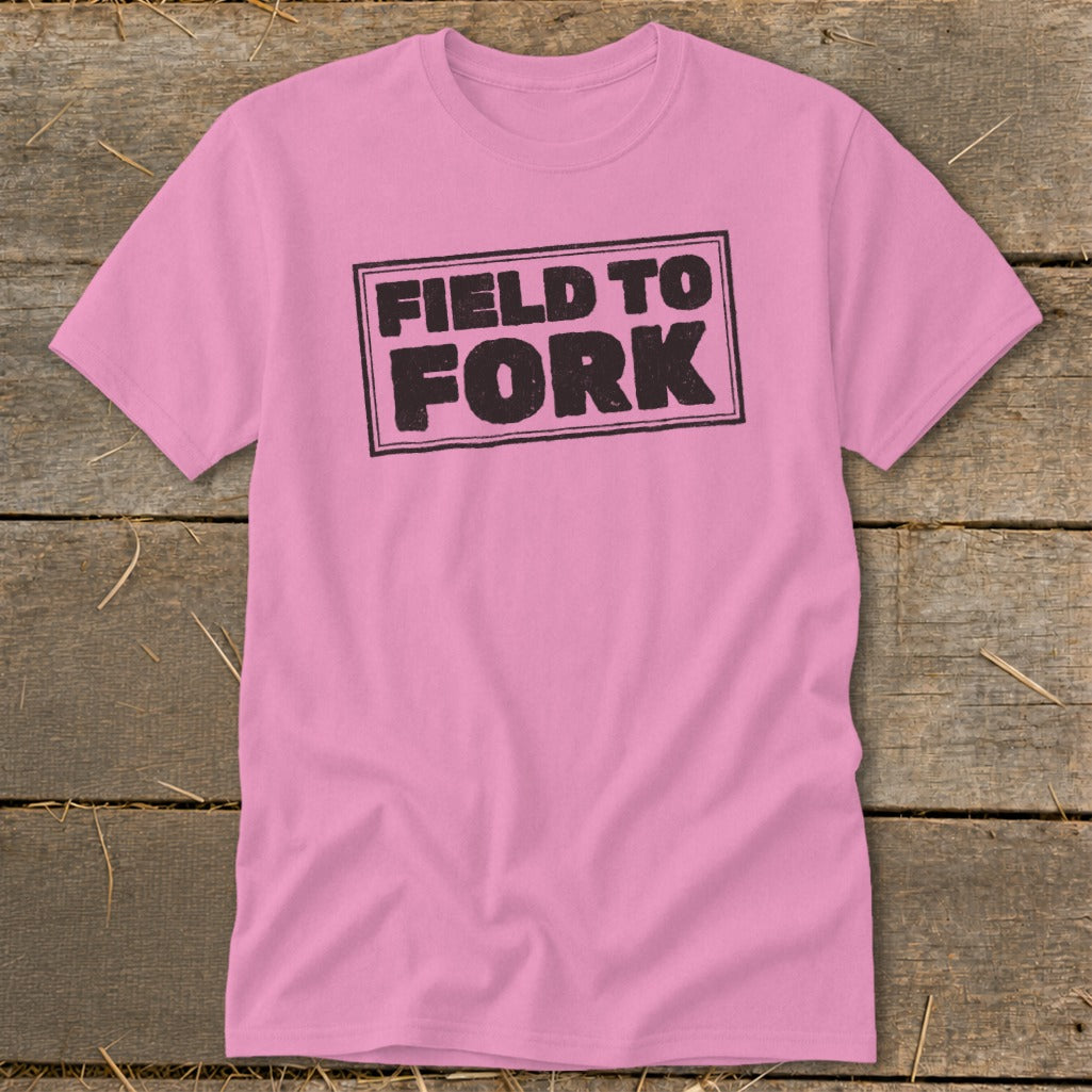 A pink short-sleeve t-shirt with a black distressed box design reading Field to Fork centered on the chest.