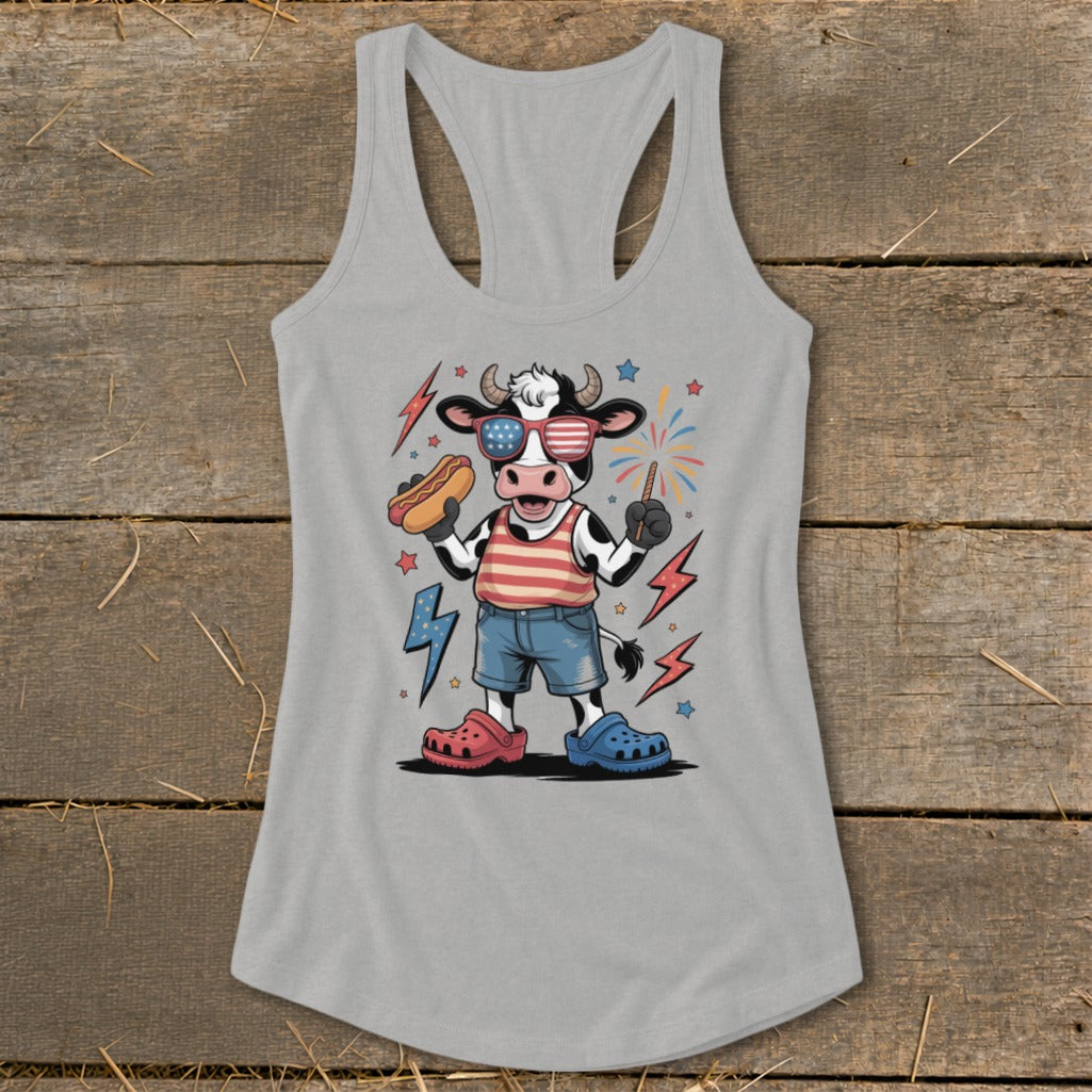 Cow wearing sunglasses and holding a hot dog with fireworks.