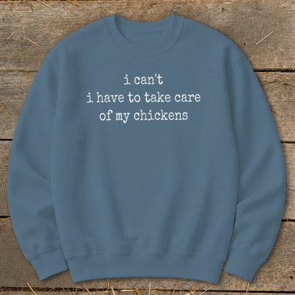 Blue sweatshirt with white text reading "i can't i have to take care of my chickens."
