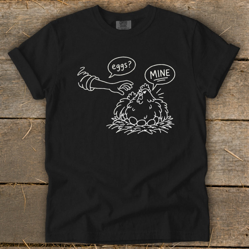 Black t-shirt with graphic of a hen protecting eggs, saying "MINE."