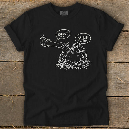 Black t-shirt with graphic of a hen protecting eggs, saying "MINE."