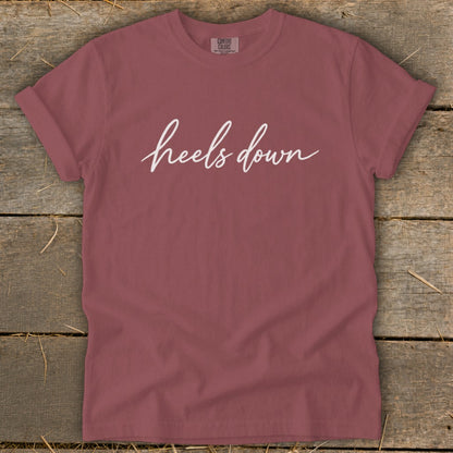 Rose comfort colors t-shirt with white "heels down" script text.