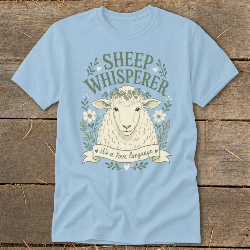 Light blue t-shirt with a sheep, flowers, leaves, and text "SHEEP WHISPERER it's a love language".