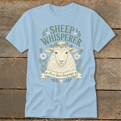 Light blue t-shirt with a sheep, flowers, leaves, and text "SHEEP WHISPERER it's a love language".