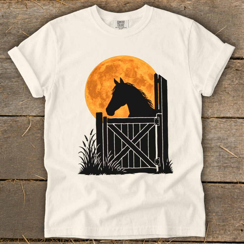 Off-white crewneck t-shirt featuring a black silhouette graphic of a horse looking over a stable door against an orange full moon.