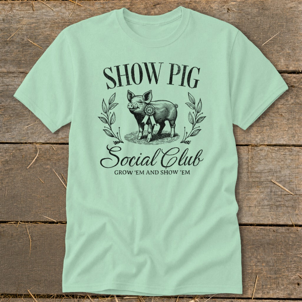 Light green t-shirt with "Show Pig Social Club" text and a pig graphic.