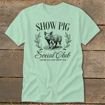 Light green t-shirt with "Show Pig Social Club" text and a pig graphic.