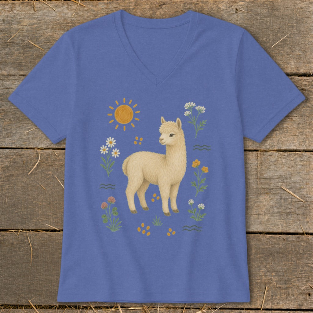 Cream alpaca illustration with sun, flowers, and wavy lines on a blue v-neck shirt.