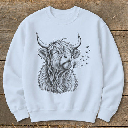 White sweatshirt with a black and white drawing of a highland cow blowing dandelion seeds.