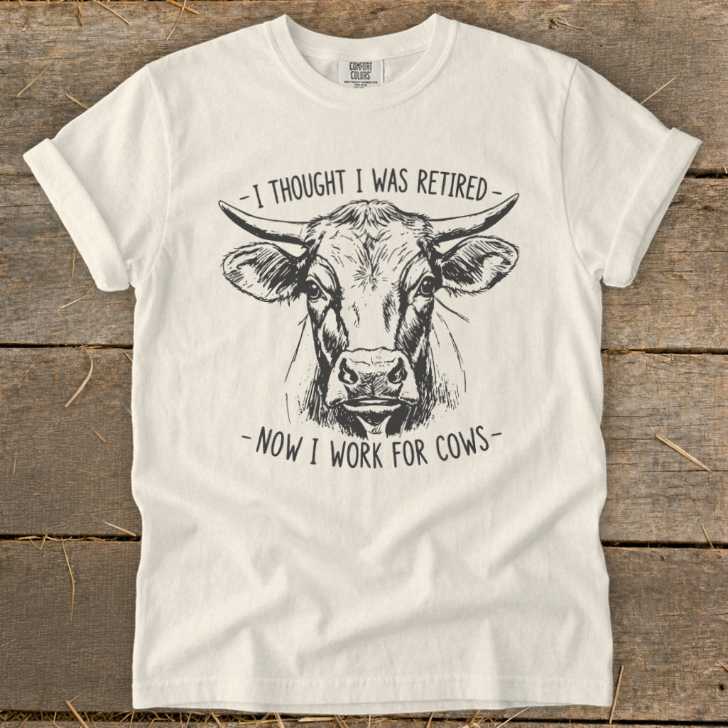 White t-shirt with a sketch of a cow and text: "I thought I was retired - Now I work for cows."
