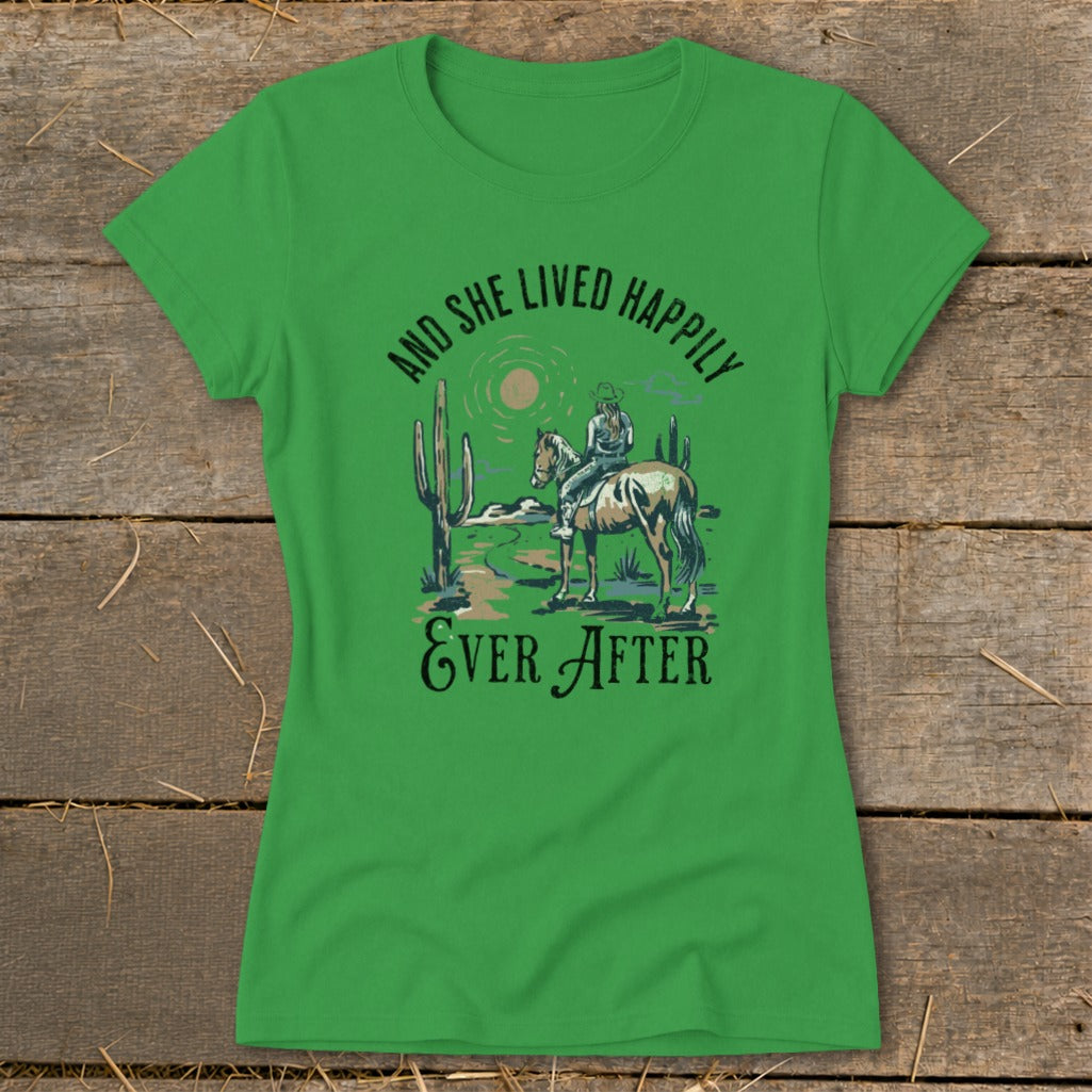 Green t-shirt with illustration of a cowgirl on horseback in the desert, "And She Lived Happily Ever After".
