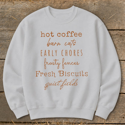 White sweatshirt with "hot coffee, barn cats, early chores, frosty fences, fresh biscuits, quiet fields" text.