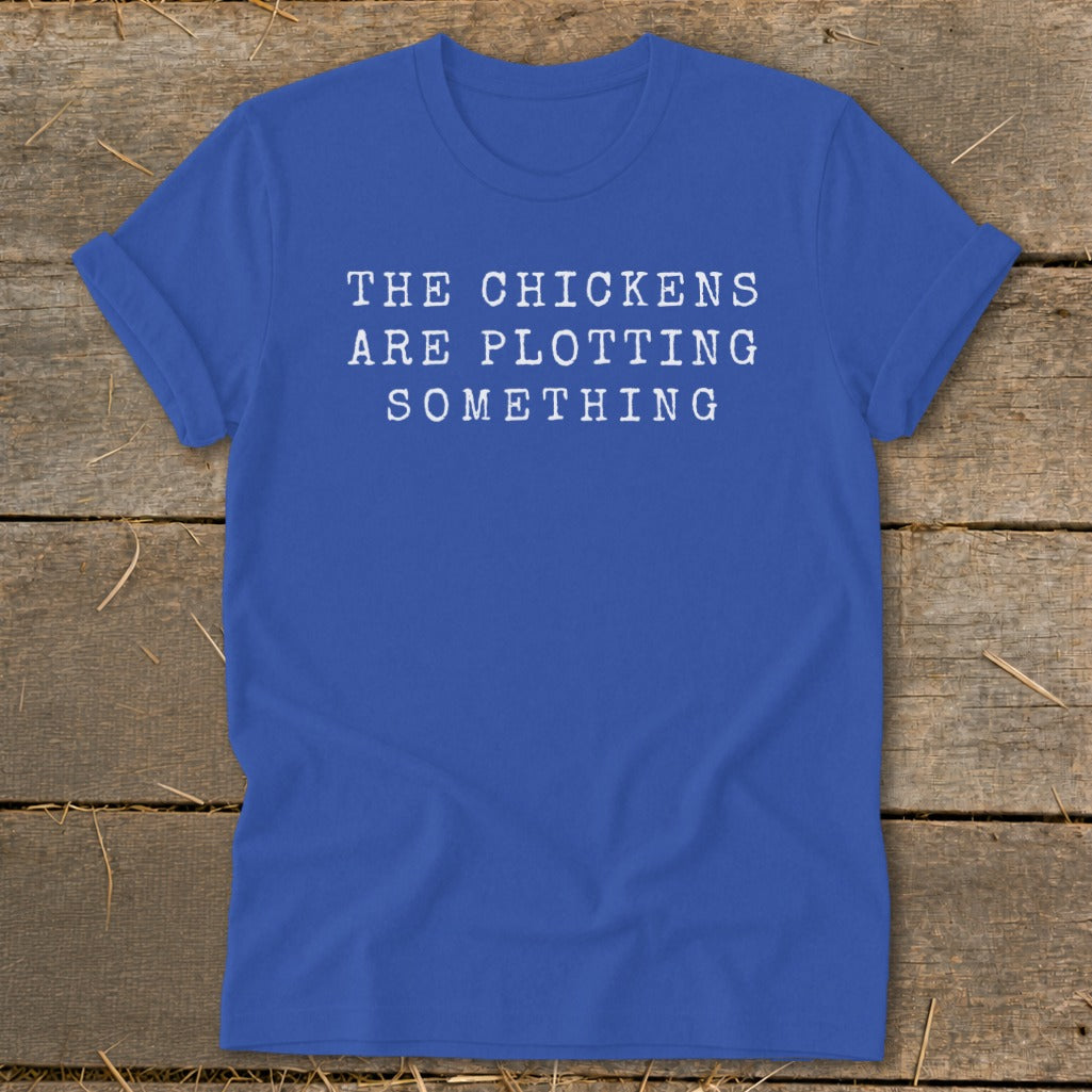 Blue t-shirt with white text reading "THE CHICKENS ARE PLOTTING SOMETHING".