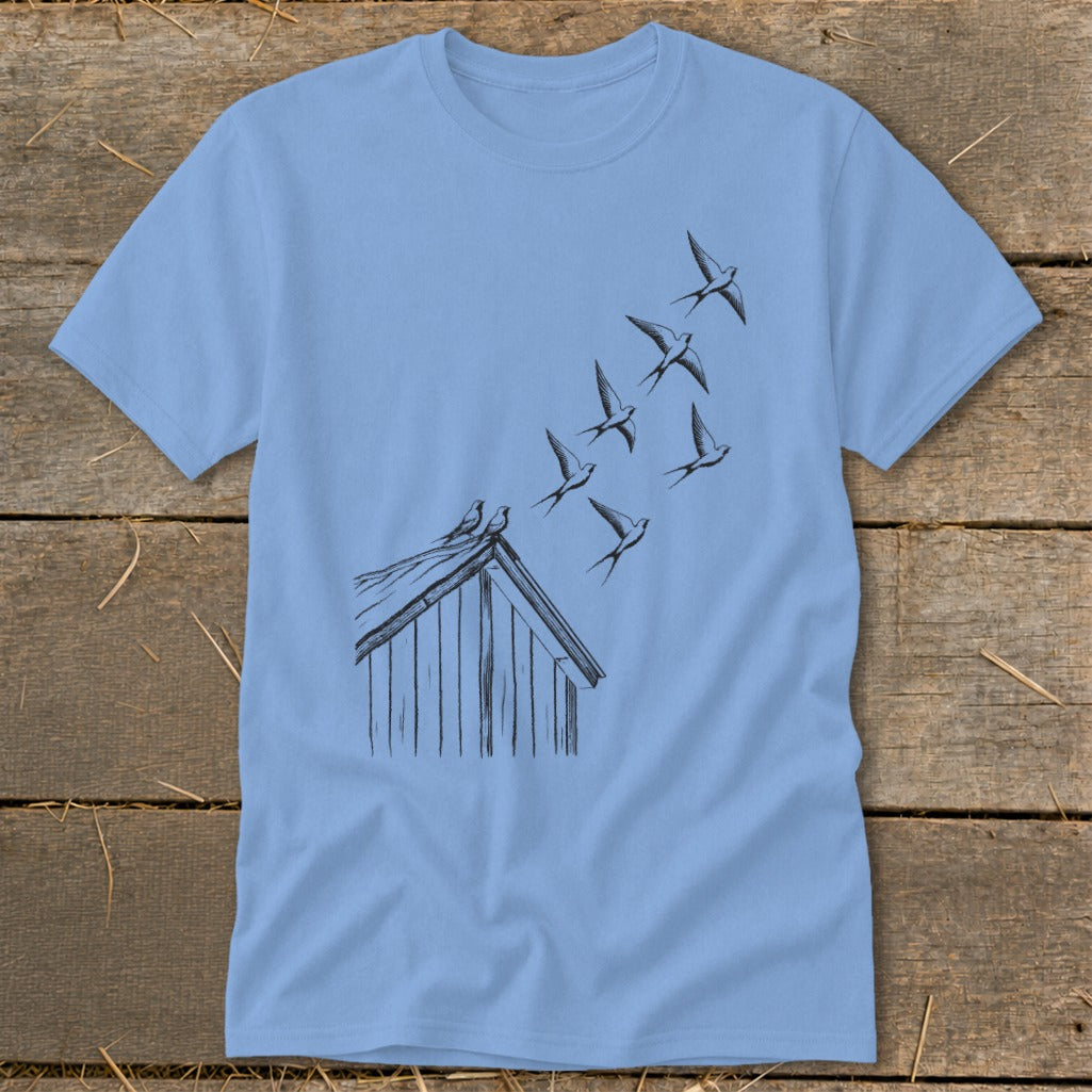 A light blue t-shirt printed with a black ink illustration of birds flying from a rooftop.