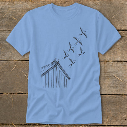 A light blue t-shirt printed with a black ink illustration of birds flying from a rooftop.