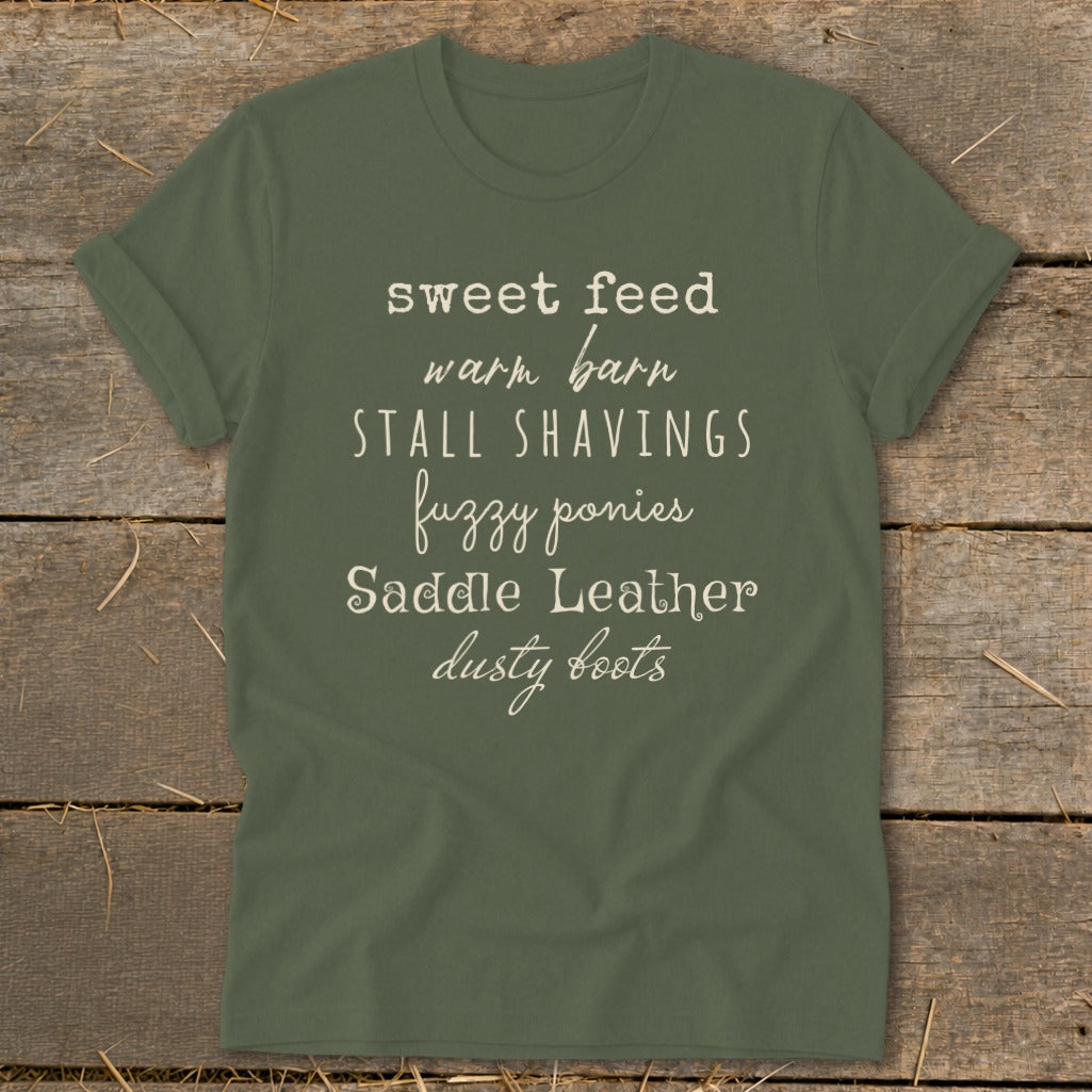 Green t-shirt with "sweet feed, warm barn, stall shavings, fuzzy ponies, saddle leather, dusty boots" text.