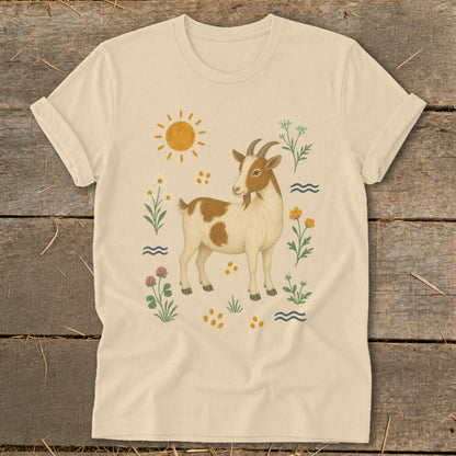 Cream t-shirt with illustration of a brown and white goat surrounded by flowers and sun.