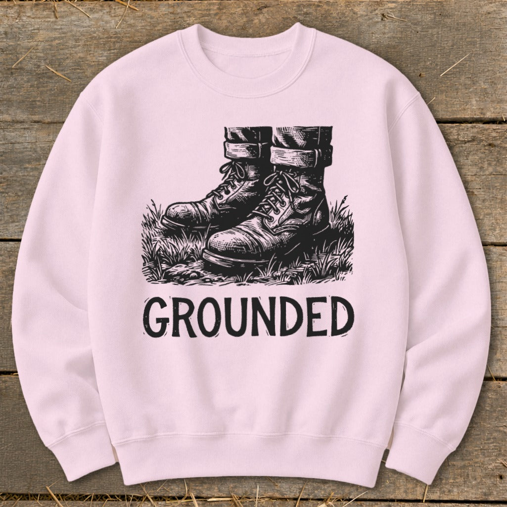 Light pink sweatshirt with black graphic of boots in grass and the word "GROUNDED".
