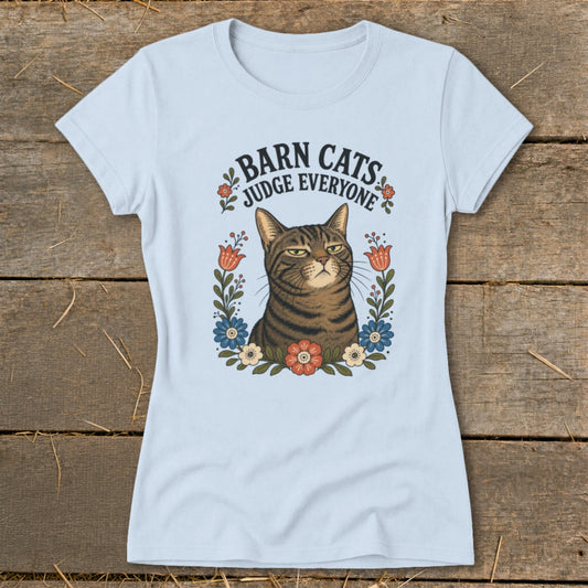 Light blue t-shirt with a grumpy tabby cat surrounded by flowers and text "Barn Cats Judge Everyone".